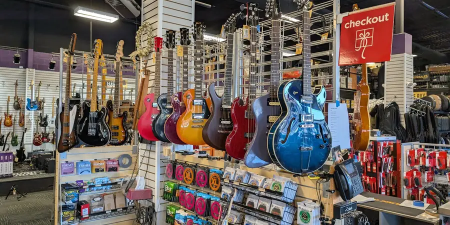 Used electric guitars and basses hanging on the wall inside Music Go Round Louisville